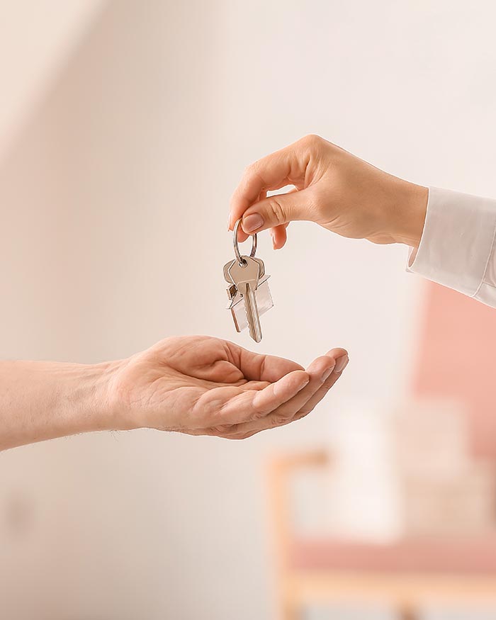 Real estate agent giving keys from house to new owner indoors